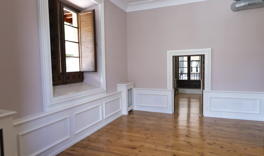 Sala del Palacio Episcopal con paredes rosas y suelo de madera, adecuada para talleres, encuentros y actividades dinámicas