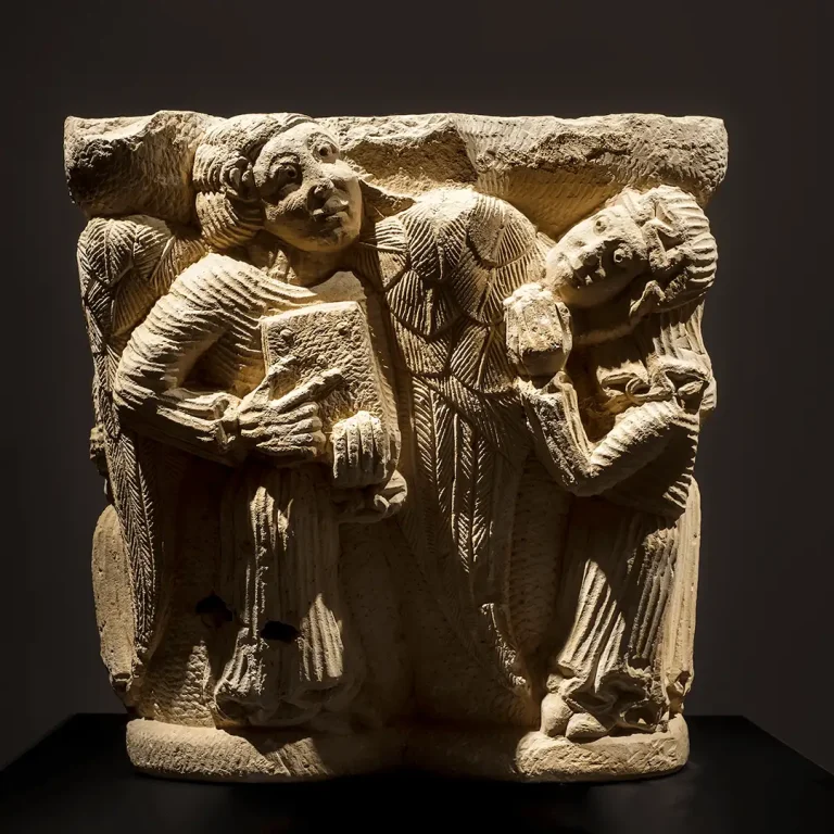 Capitel románico del siglo XIII tallado en piedra con la escena de la Anunciación y un evangelista, conservado en el Palacio Episcopal de Segovia
