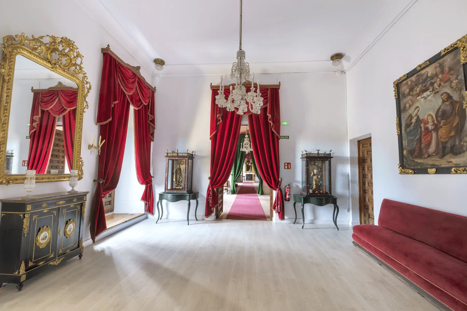 Vista de la Antesala I del Palacio Episcopal de Segovia con mobiliario de estilo francés, lámparas de cristal de Baccarat y vitrinas con imágenes religiosas